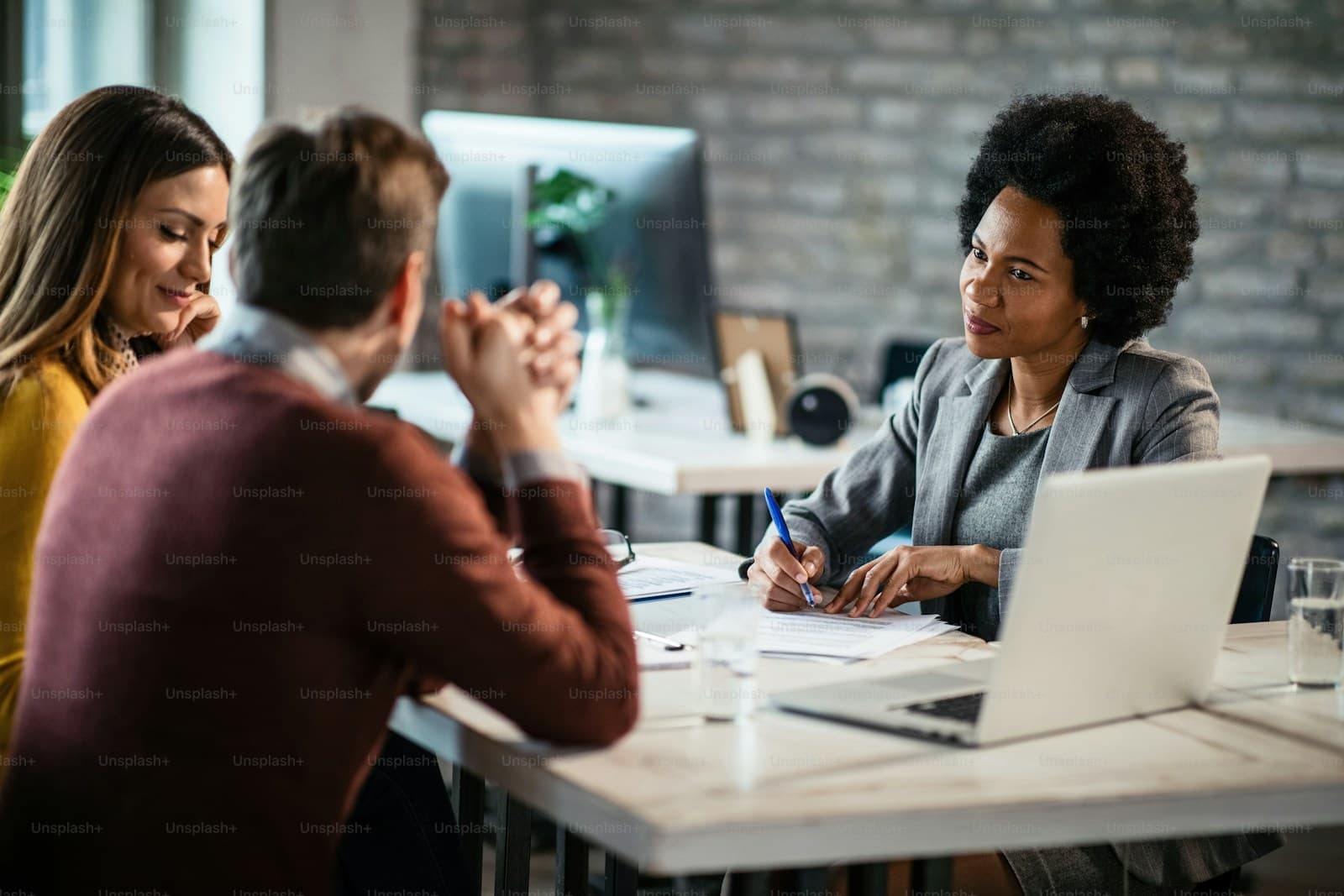 Three people meeting around a white table in a modern office