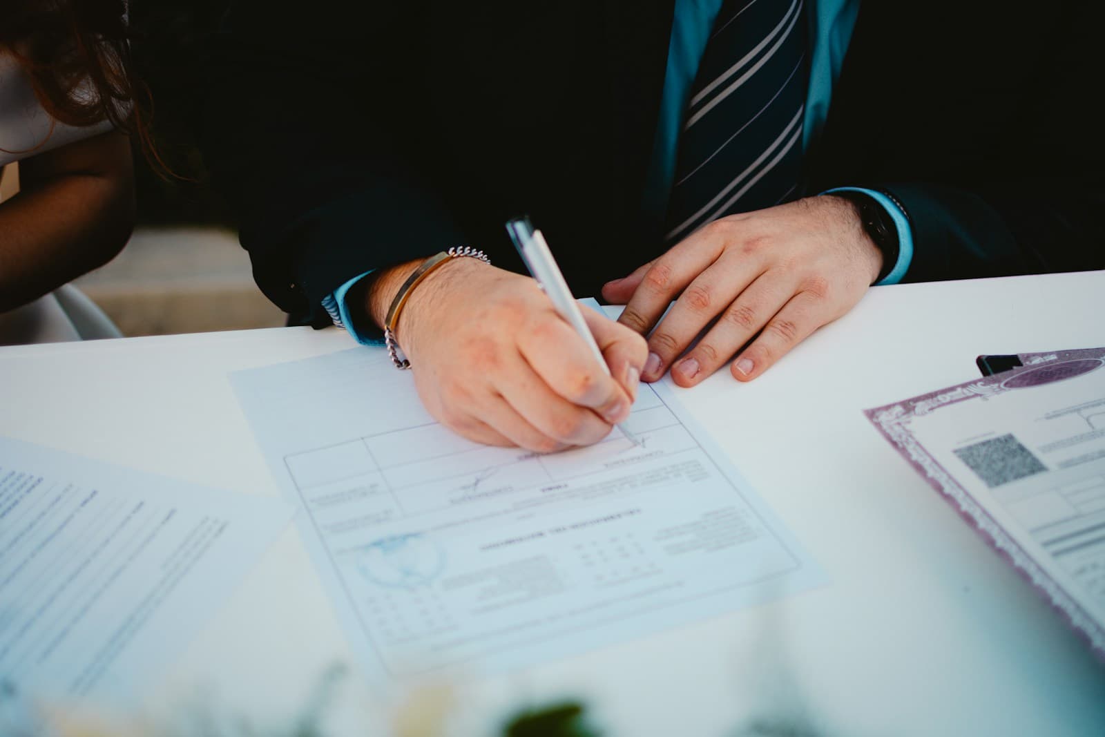 Business person in suit signing documents with pen at office desk