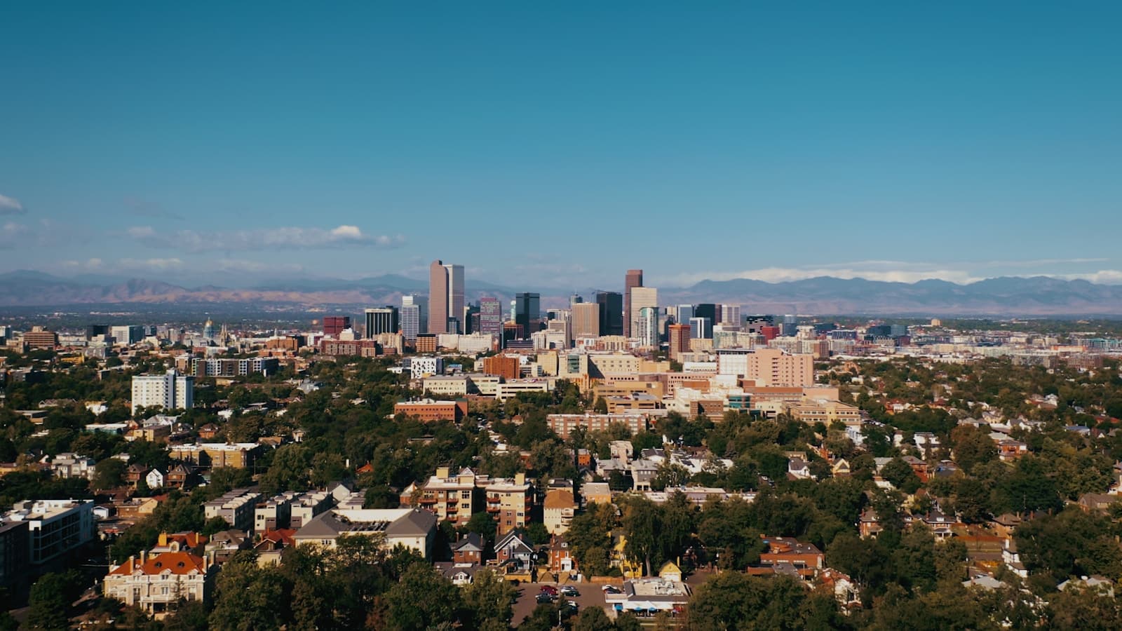 Aerial view of city skyline with downtown skyscrapers surrounded by residential neighborhoods and mountains