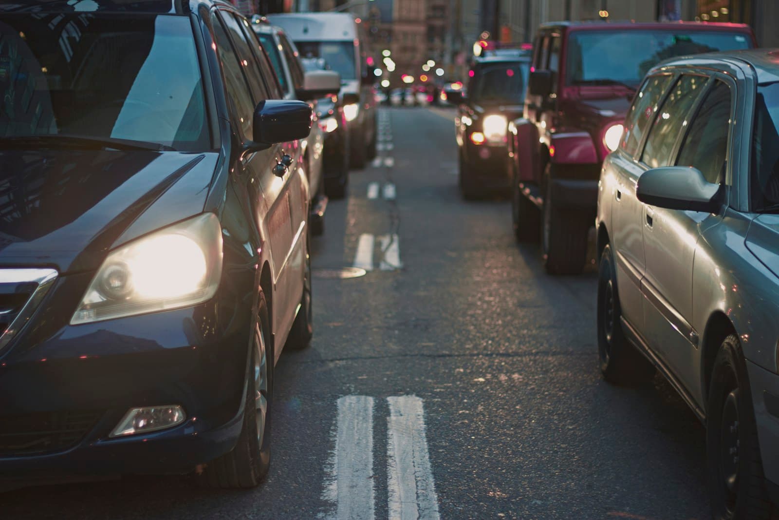 Heavy traffic congestion on city street with cars in multiple lanes during rush hour with headlights on