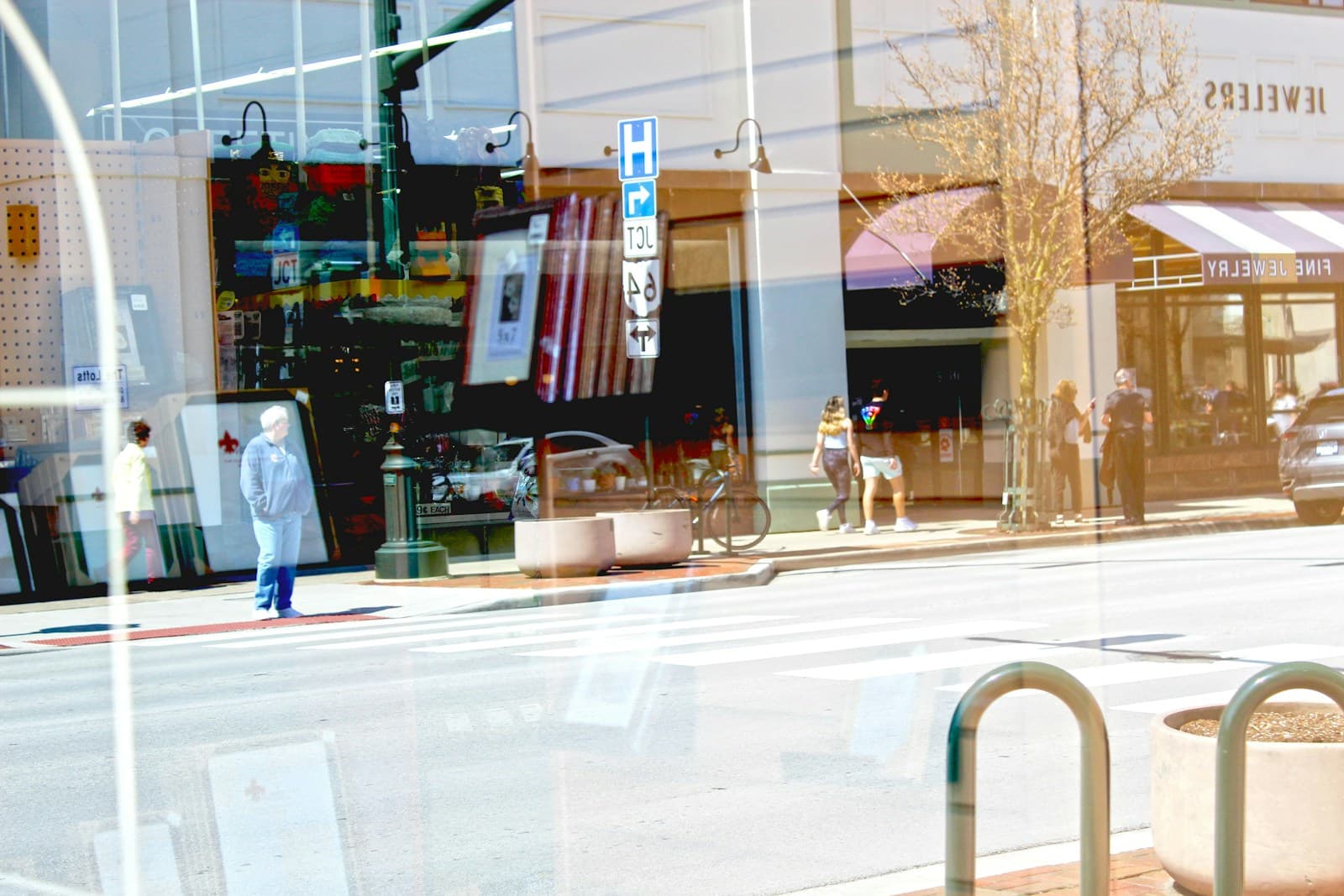 Person walking past storefronts on a commercial street with large windows and metal railings