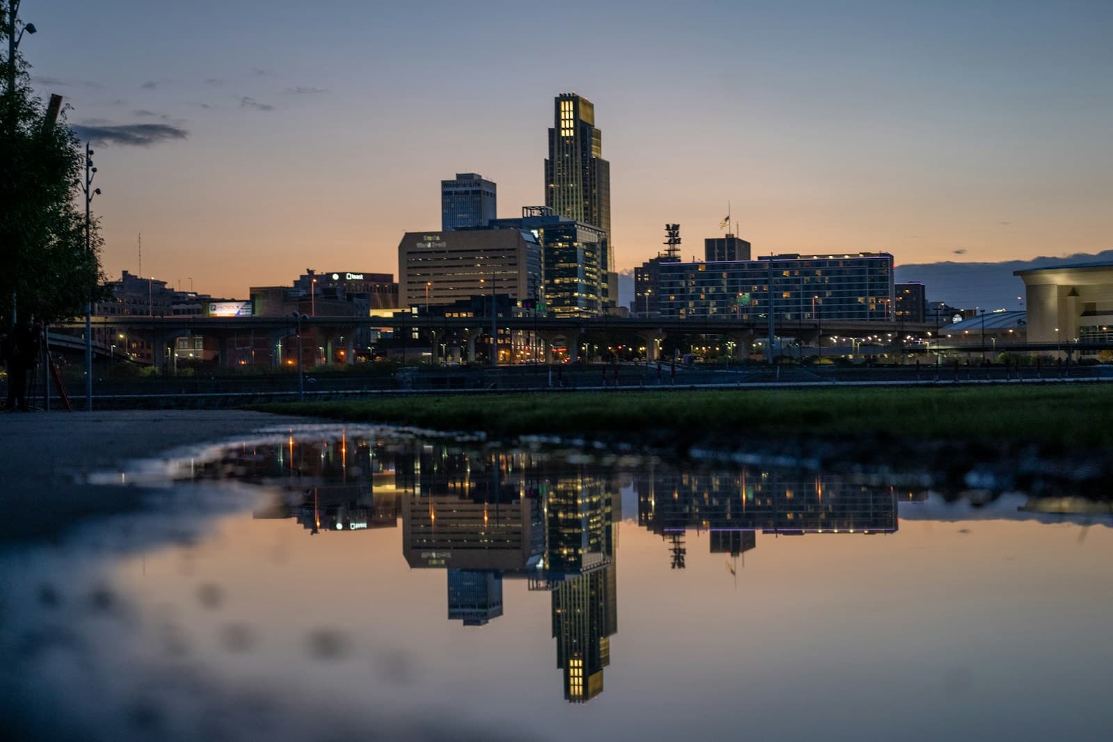 City skyline at sunset with buildings reflected in calm water during golden hour twilight