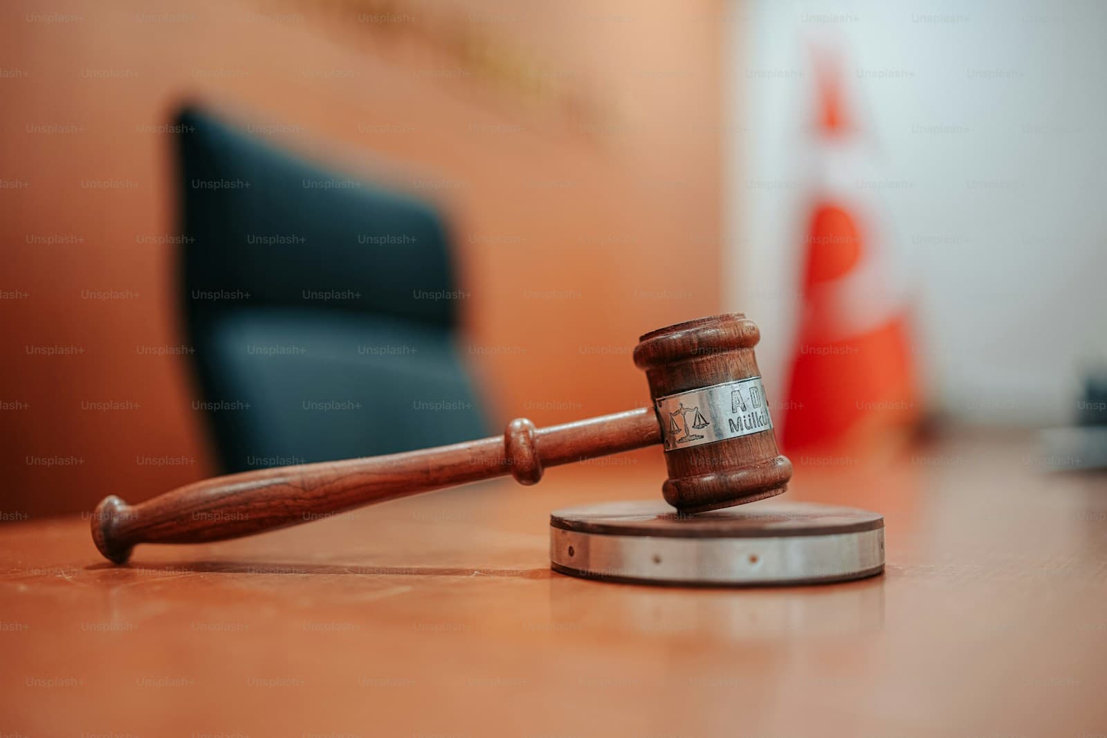 Wooden judge's gavel and sound block on wooden desk in courtroom setting