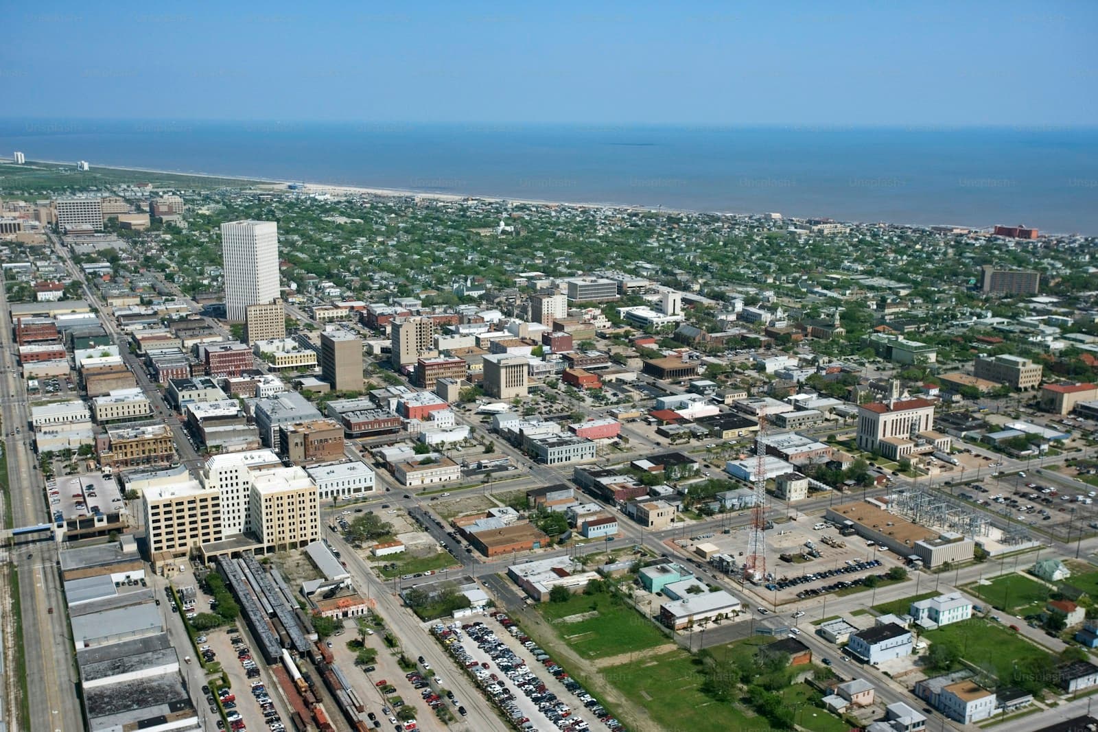 Aerial view of downtown city with tall buildings, residential areas, and water visible in the distance