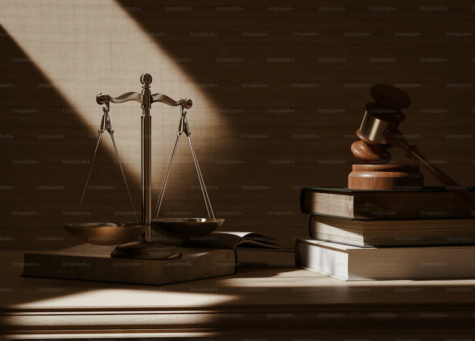 Scales of justice and wooden gavel on stack of law books with dramatic lighting