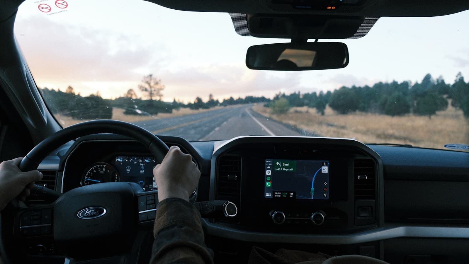 Driver on a rural highway at sunset with the Ford dashboard display lit
