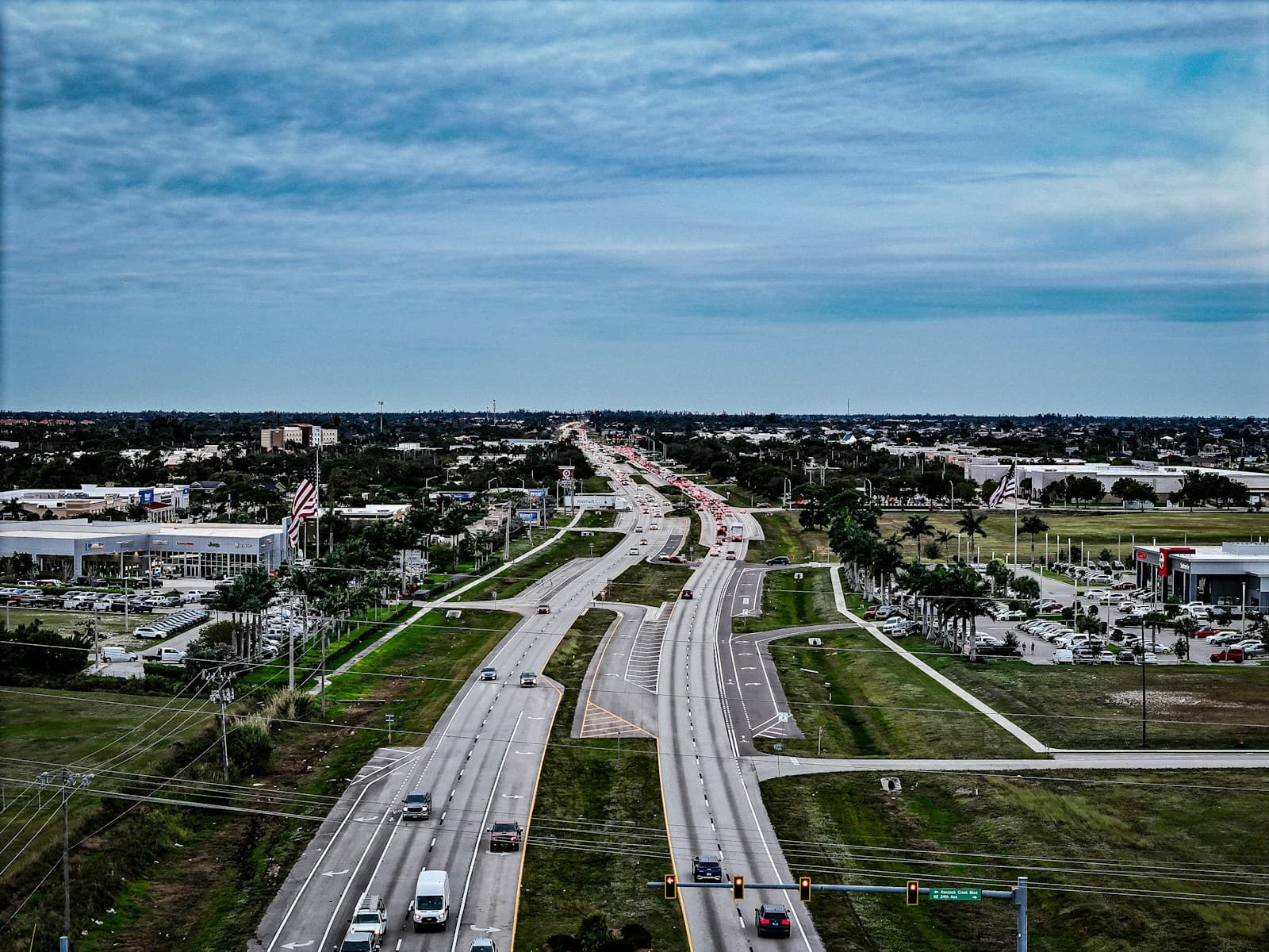 Aerial view of wide divided highway with median strip running through suburban commercial area under cloudy sky