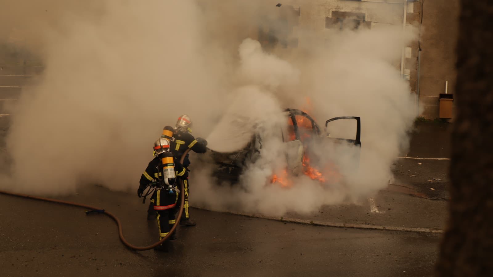 Firefighters battling a car fire with thick smoke in an underground garage or tunnel