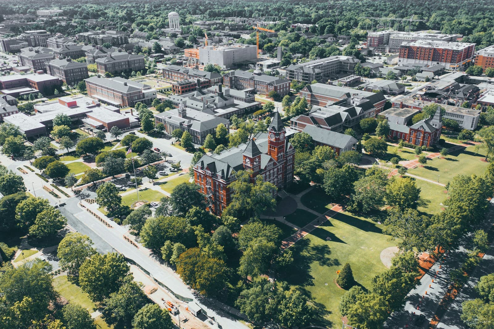 Aerial view of university campus with red brick buildings, green lawns, and tree-lined pathways