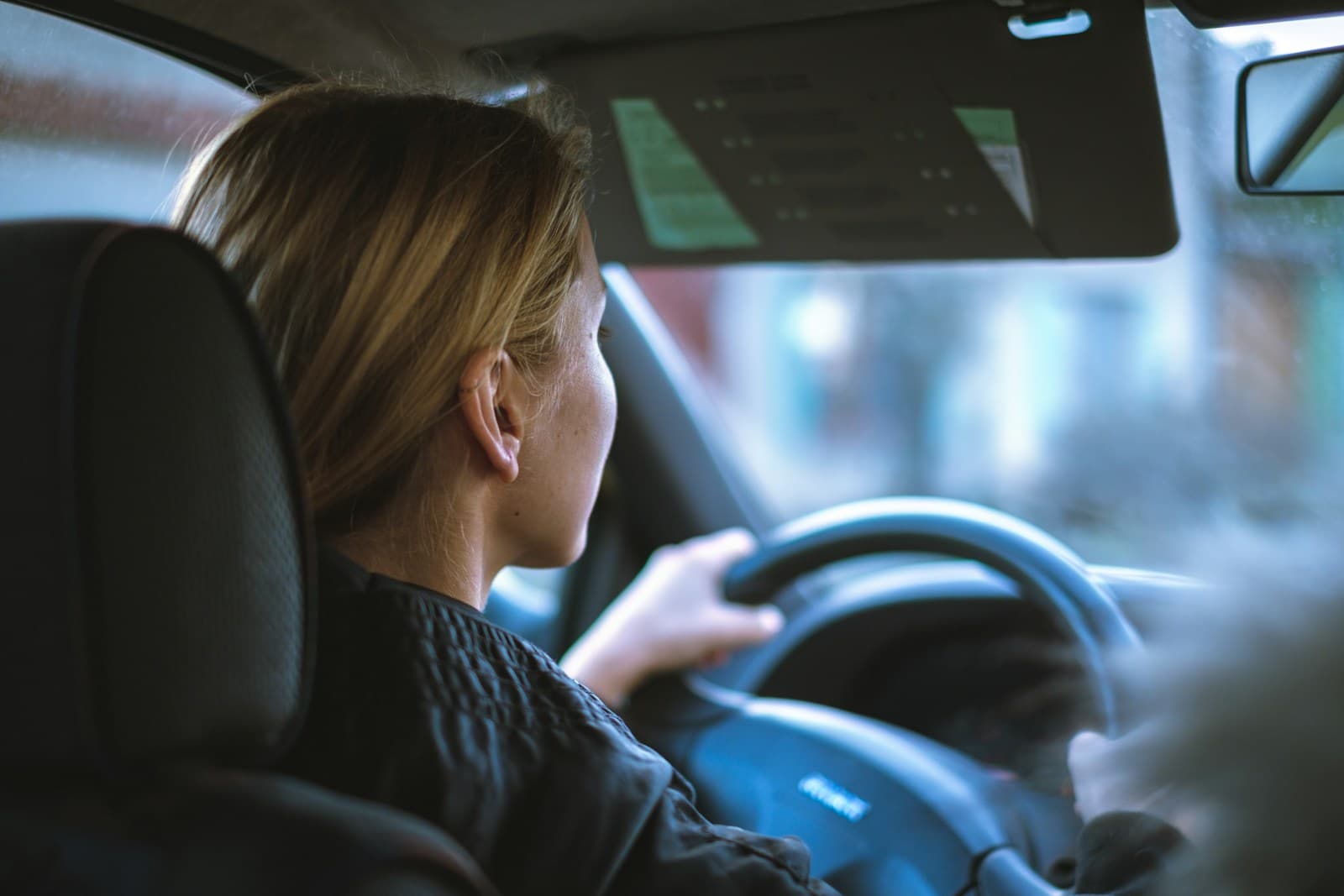 Blonde woman gripping the steering wheel while driving in natural daylight