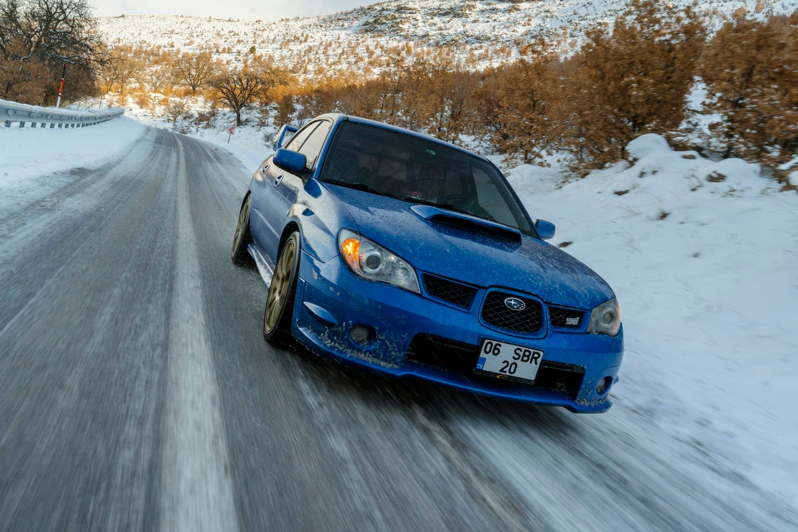 Blue Subaru WRX STI driving on snowy mountain road with motion blur