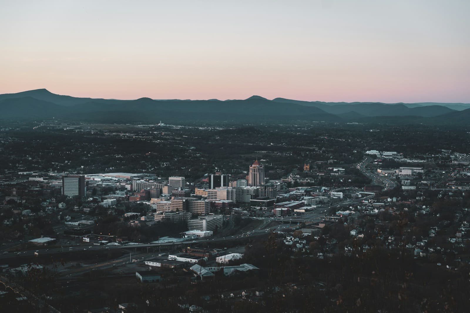 Aerial view of city skyline at twilight with downtown buildings and mountains in background