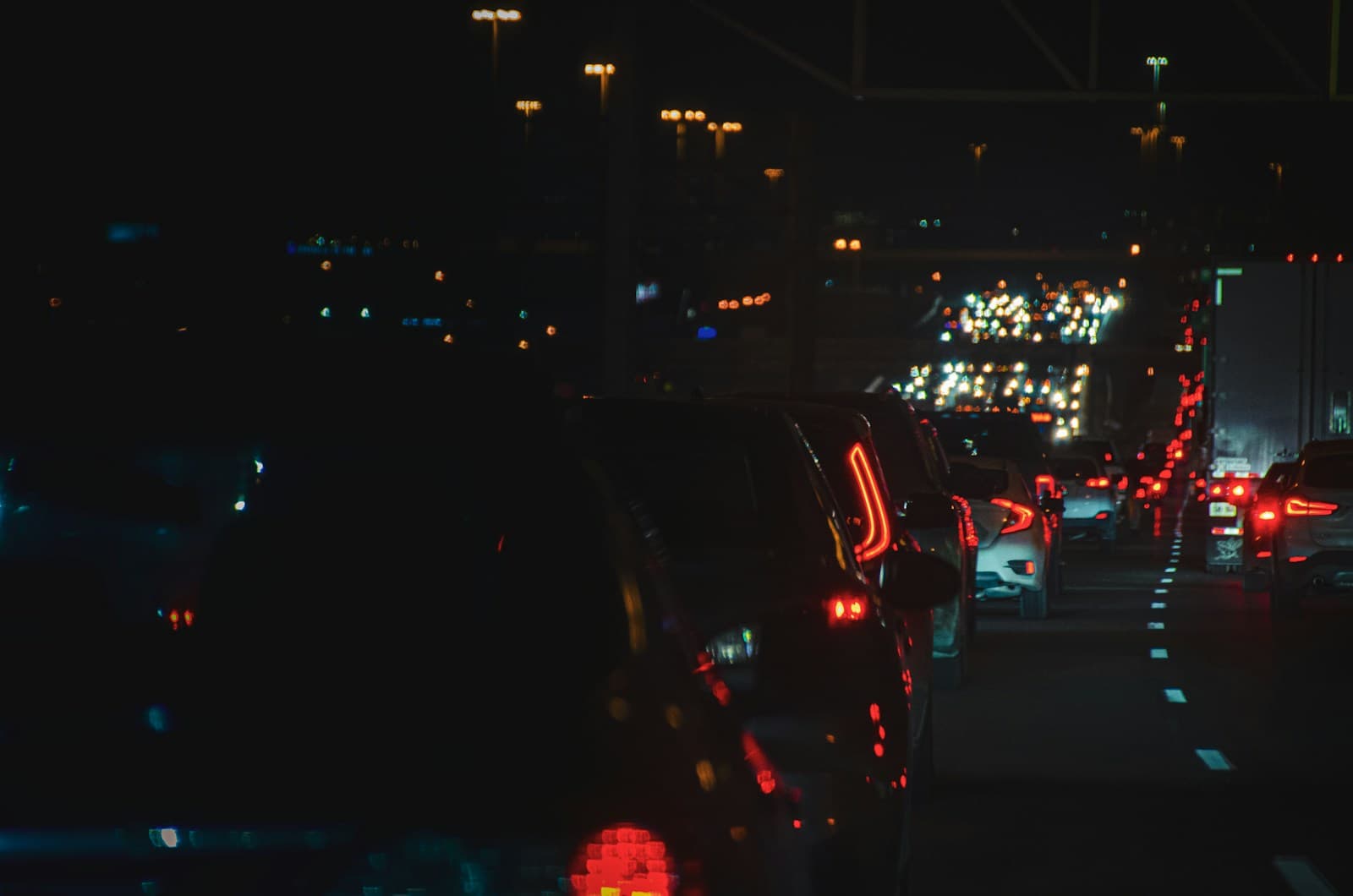 Night traffic scene with cars in congestion, red tail lights and illuminated buildings in background