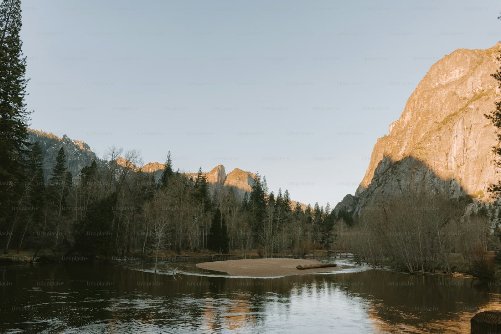 Mountain landscape with granite cliffs reflected in calm water during golden hour sunset