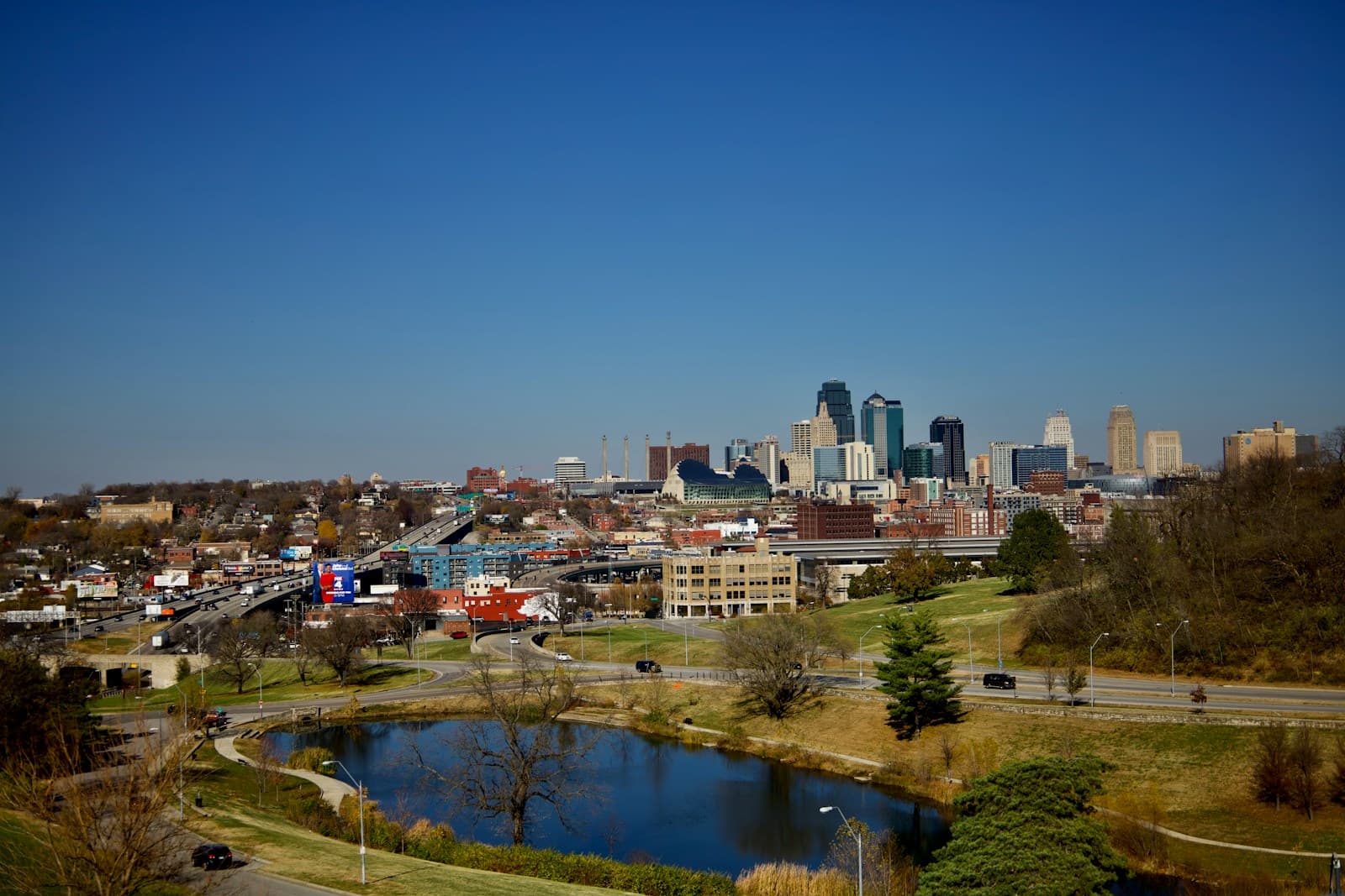 City skyline view with downtown buildings in background and residential area with pond and parkland in foreground