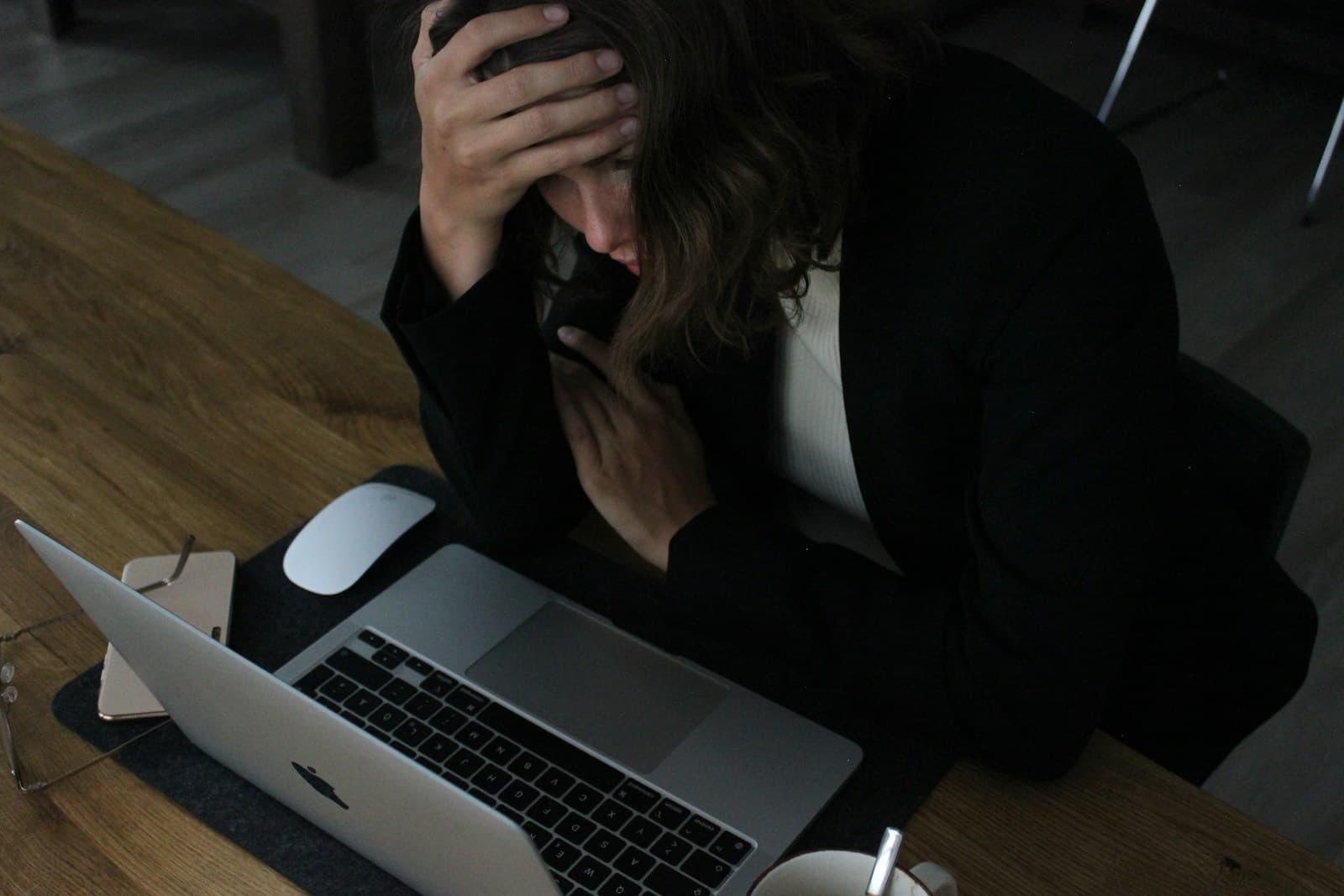 Person with head in hands sitting at desk with laptop, showing workplace stress or fatigue