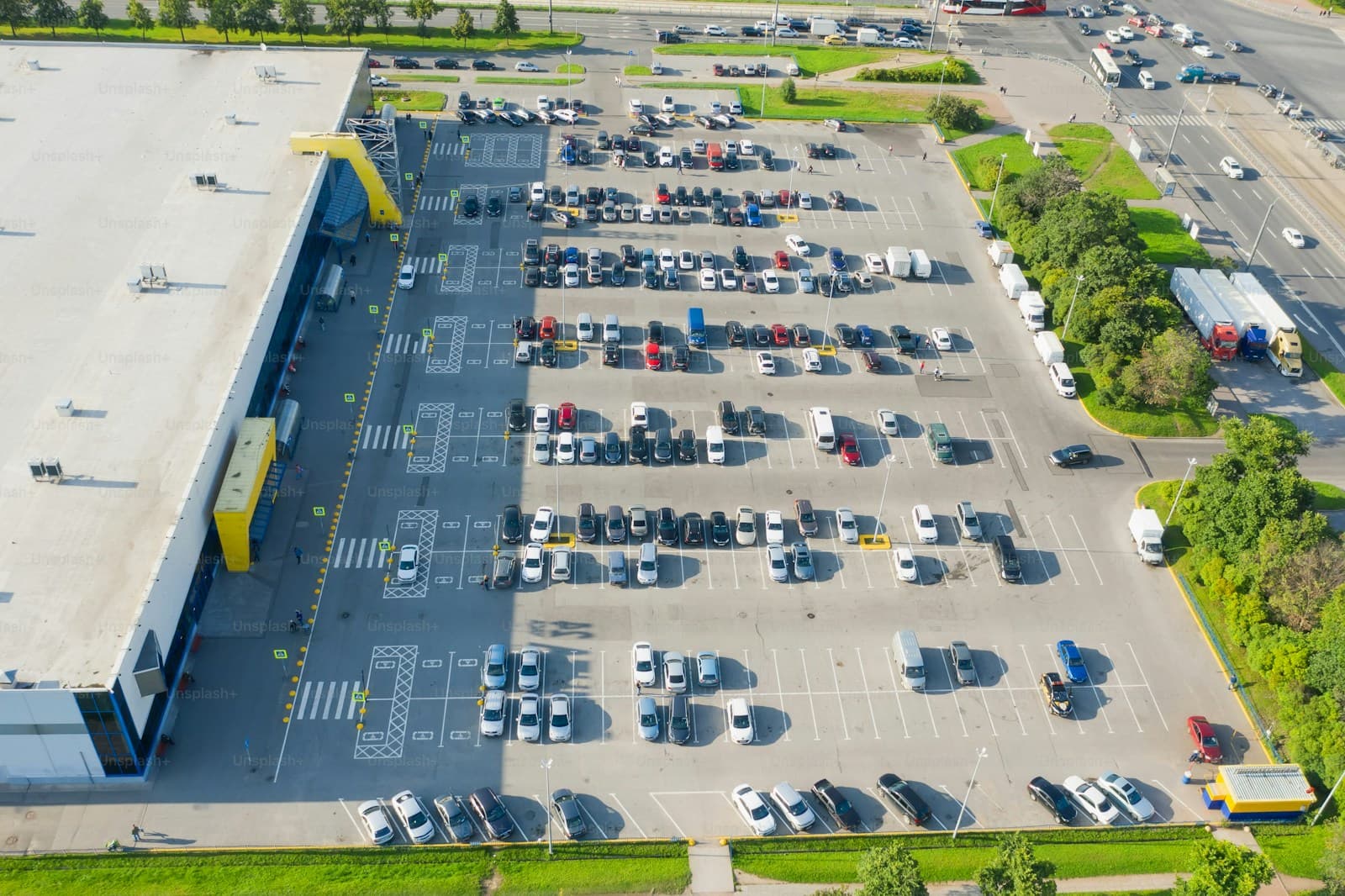 Aerial view of large retail store with yellow facade and crowded parking lot full of cars