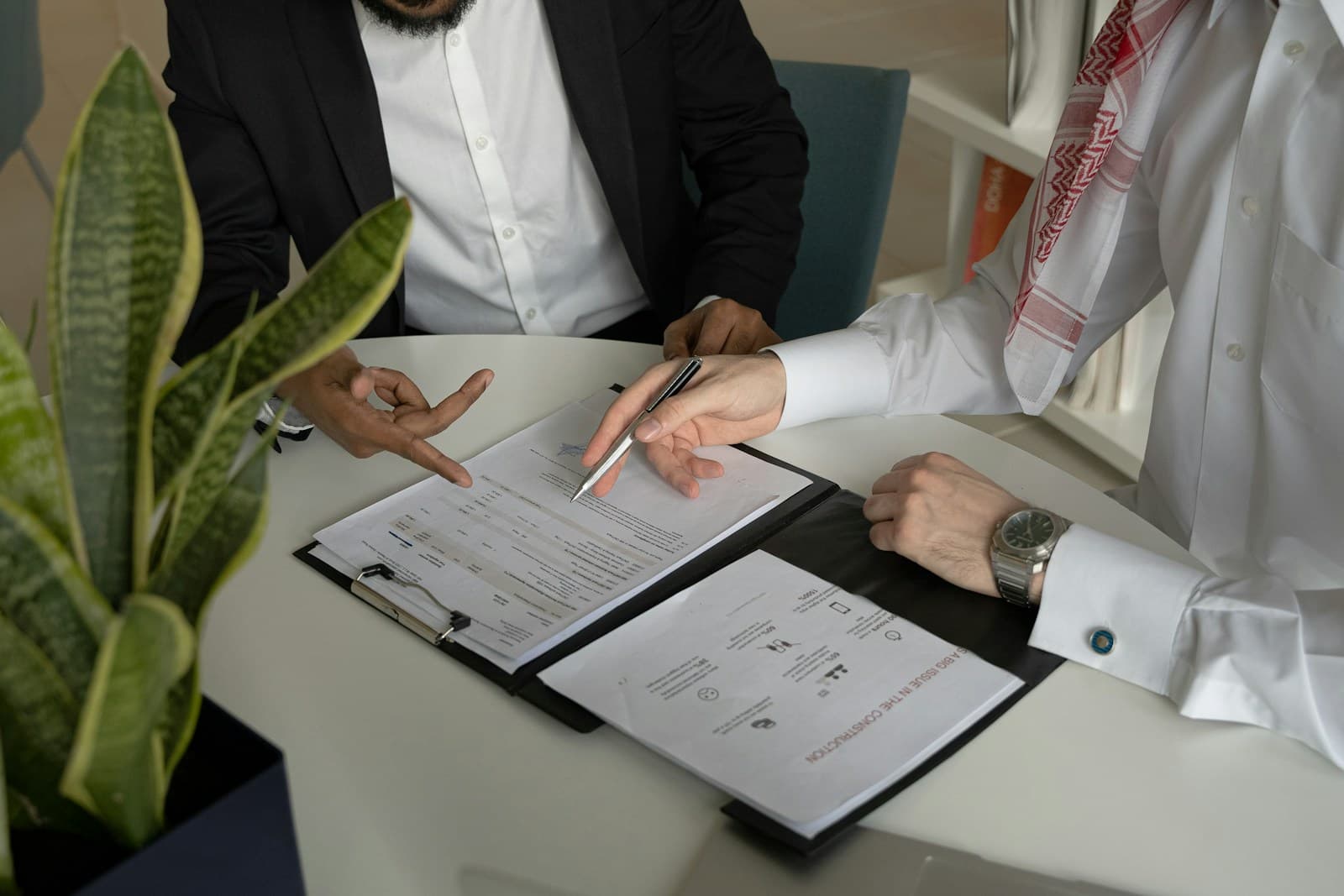 Two men in business attire reviewing documents together at a white table