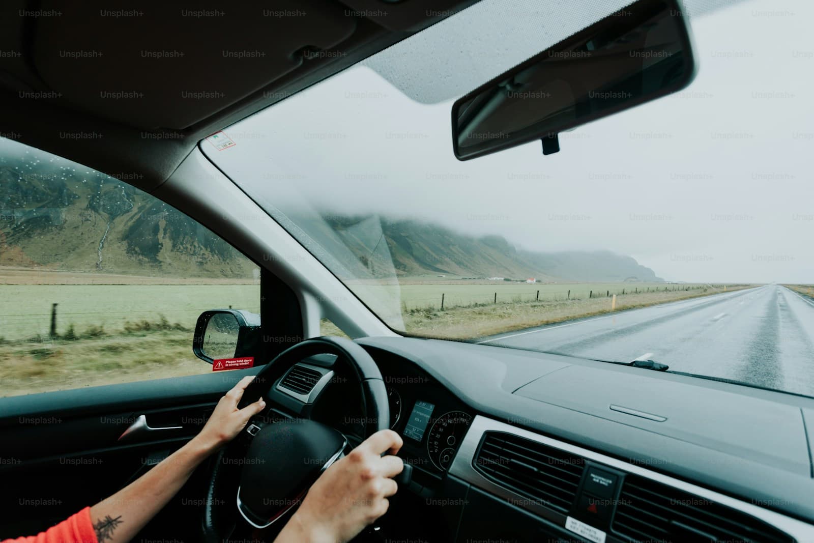 Driver on a straight desert highway with mountains fading into distant fog