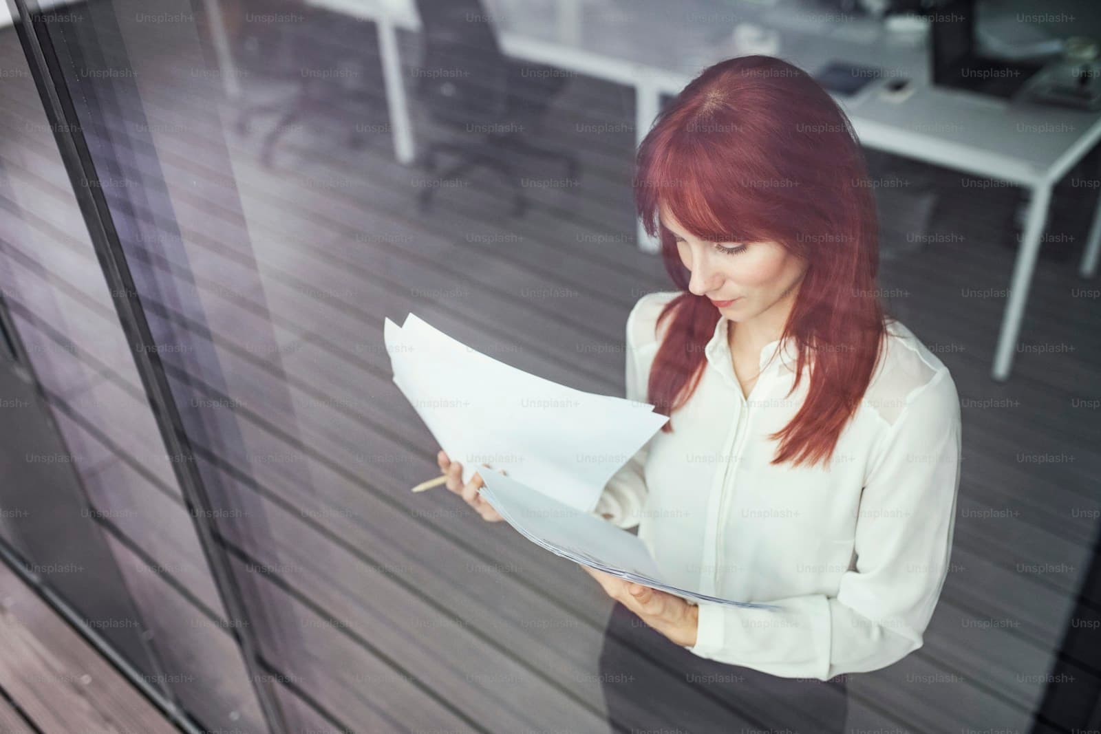 Professional woman in blazer reading documents on modern wooden deck