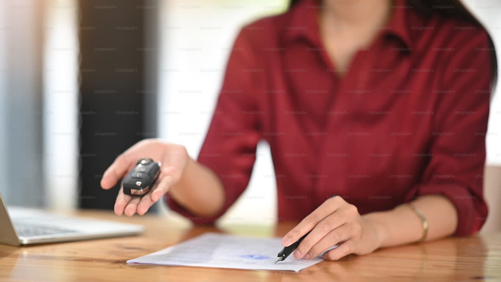 Person in a red shirt at a wooden table holding a small electronic key device