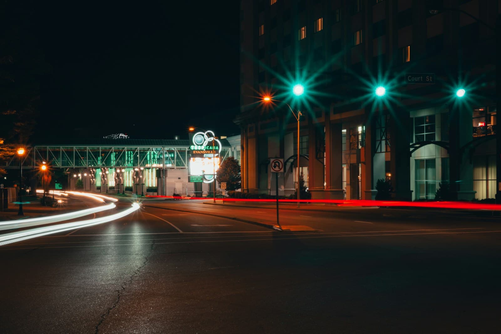 Night street scene with car light trails and illuminated streetlamps creating long exposure effect