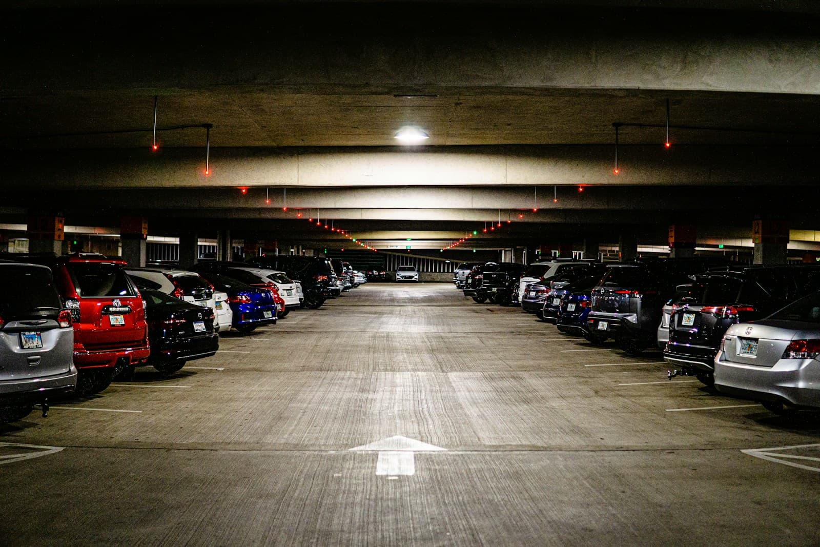 Underground parking garage with rows of parked cars on both sides of a central driving lane